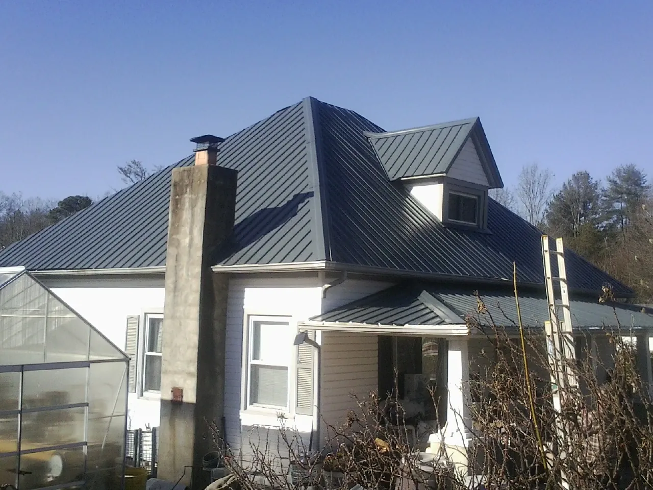 Dark blue standing seam metal roof on a white farmhouse with dormer — Slate & Tile Roof Repair by Roofing Brothers in Elderton