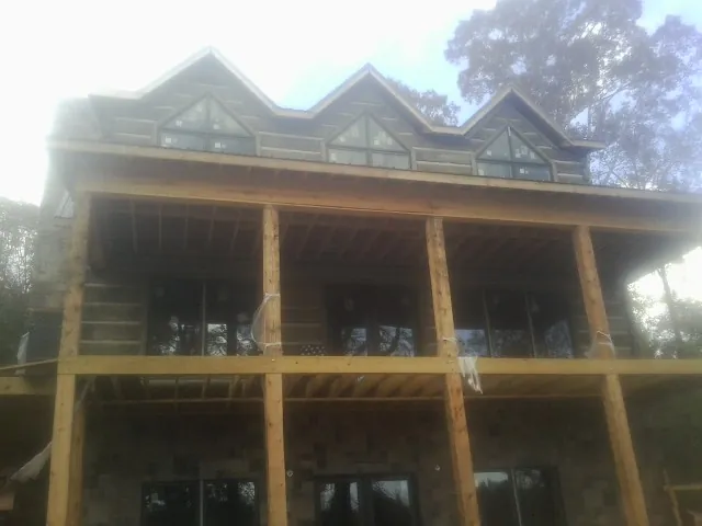 Dormers and porch framing on a large log home under construction — Roof Coating work by our crew in Elderton