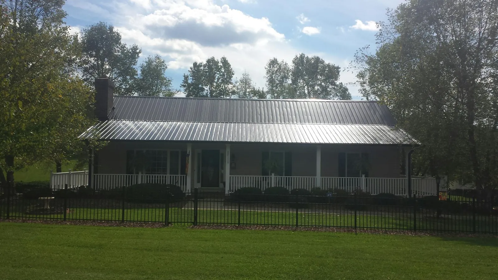 Gray metal roof on a brick ranch with a full width front porch — Gutter Guard Installation work by our crew in Elderton