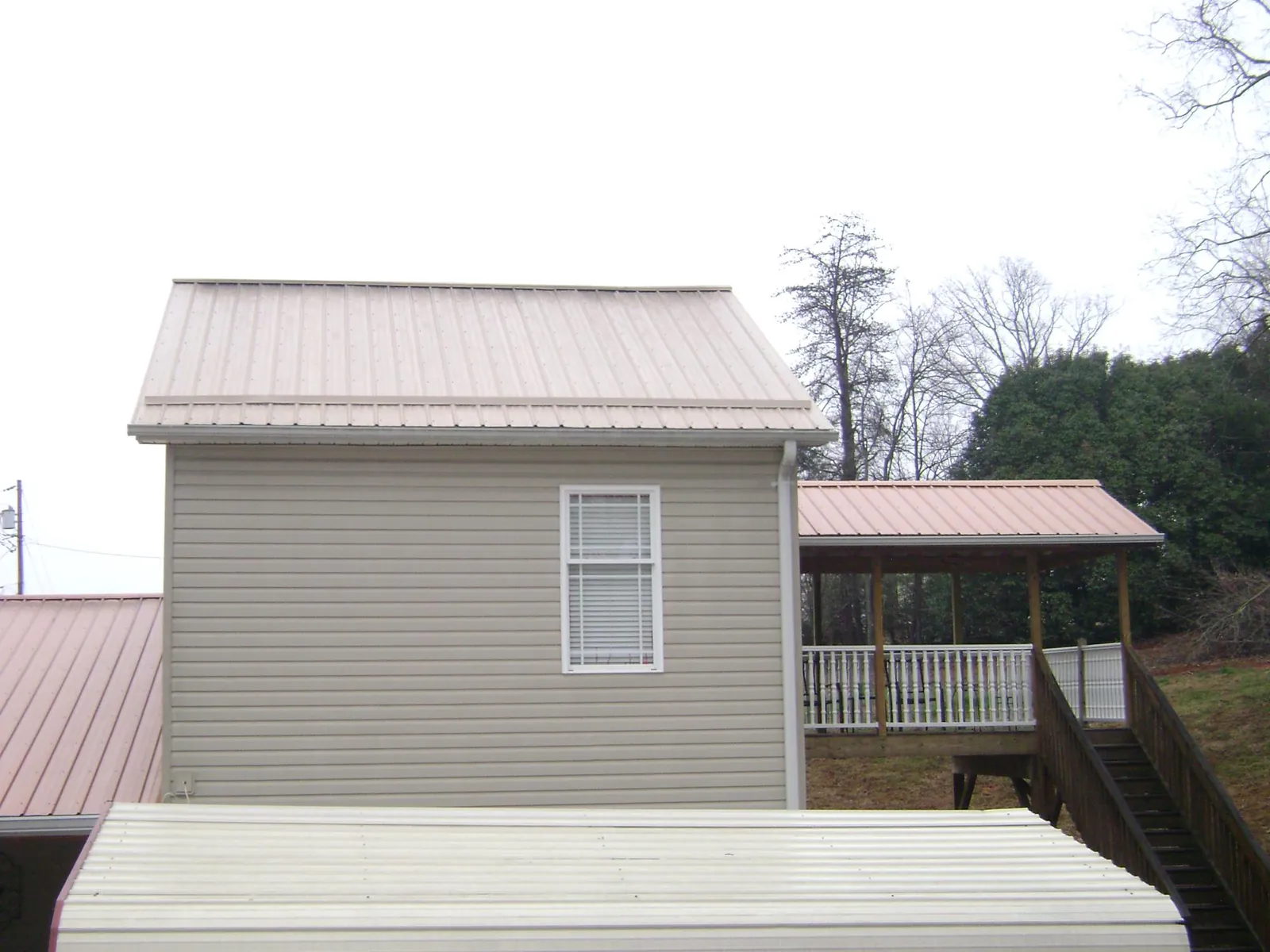 Tan metal roofs on a two story addition and attached porch, from a Roof Replacement job in Elderton