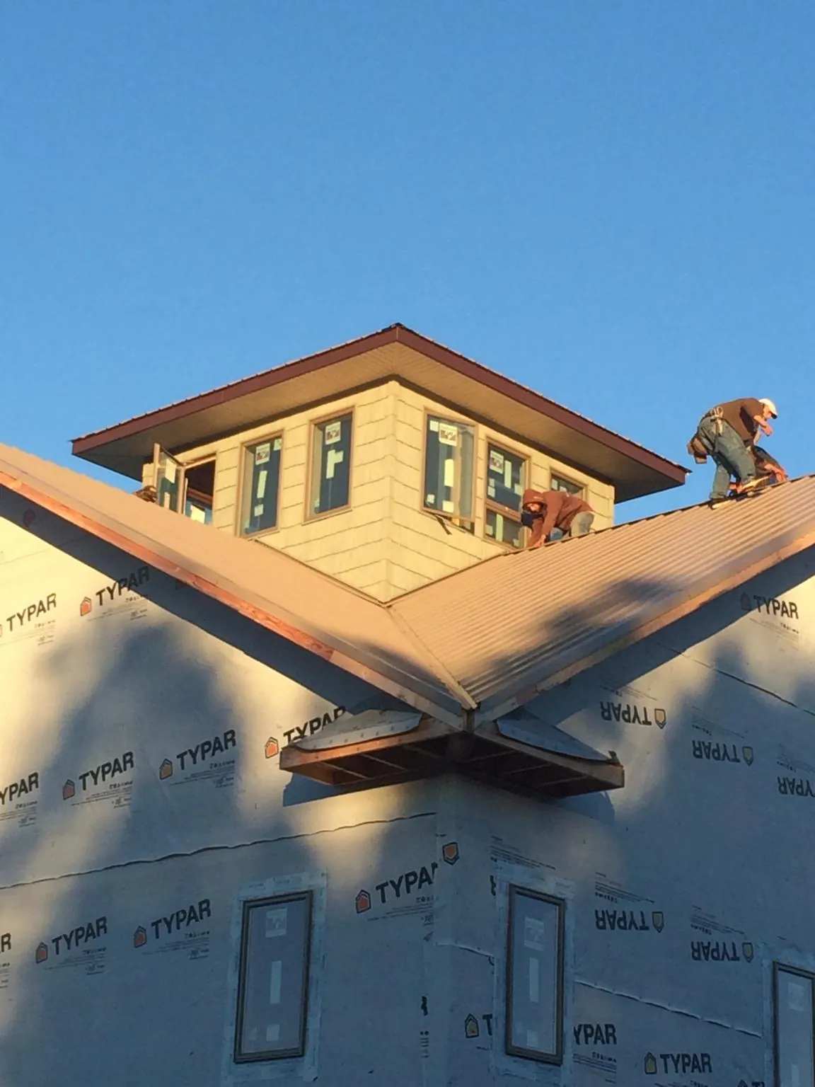 Roofers working around a rooftop cupola on a new metal roof at sunset — Roof Waterproofing in Elderton by Roofing Brothers
